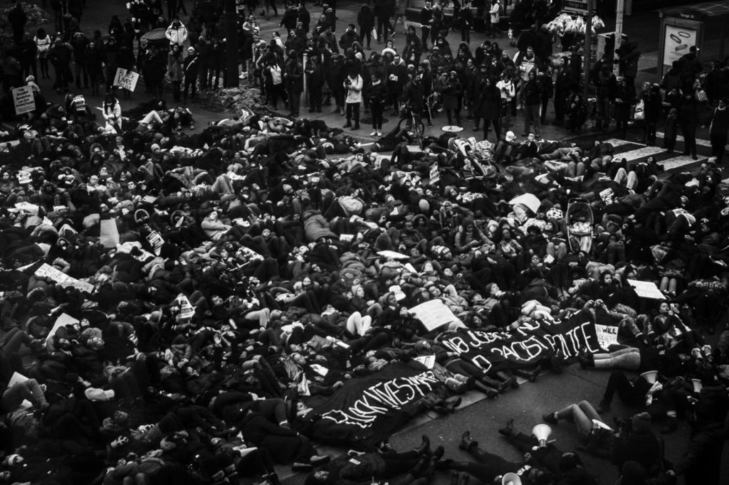 Jalani Morgan, Protesters perform a "die-in" by laying on the ground at Yonge and Dundas Square in Toronto, 2014, printed 2017 (two inkjet prints on vinyl; each approx. 243x121.92cm). AGO purchase, with funds from the Canada Now Photography Acquisition Initiative, Edward Burtynsky and Nicholas Metivier, 2021. ©Jalani Morgan. 2022/7056
