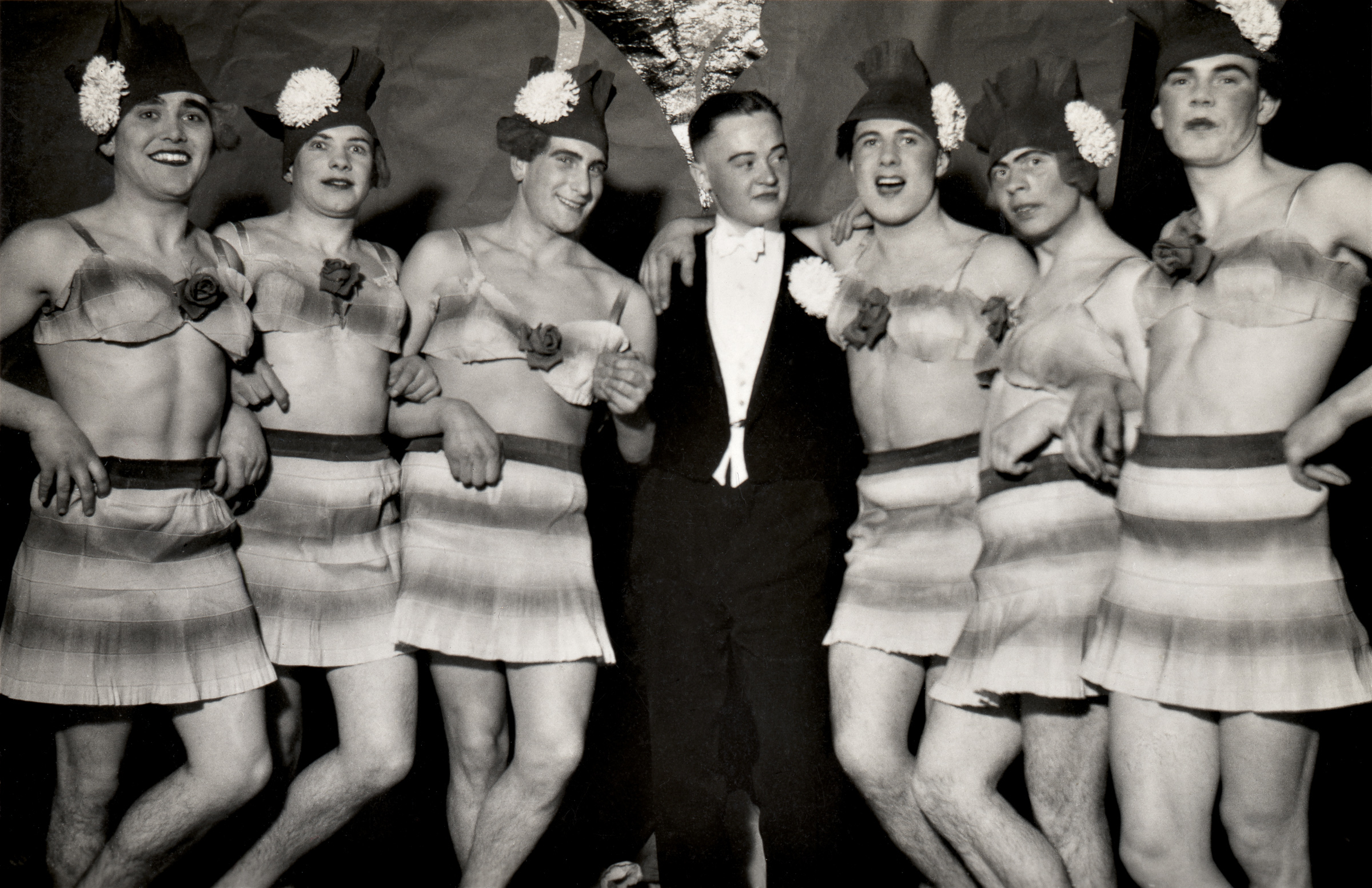     Unidentified photographer, [A tuxedo-wearing man surrounded by six male cross-dressers, with written inscription on verso “Das Ballet von Kompaniefest im Winter 1937/38 (The Kompaniefest Ballet in the Winter of 1937/38)”, Germany], 1937. © 2016 Éditions Textuel – Collection Sébastien Lifshitz

